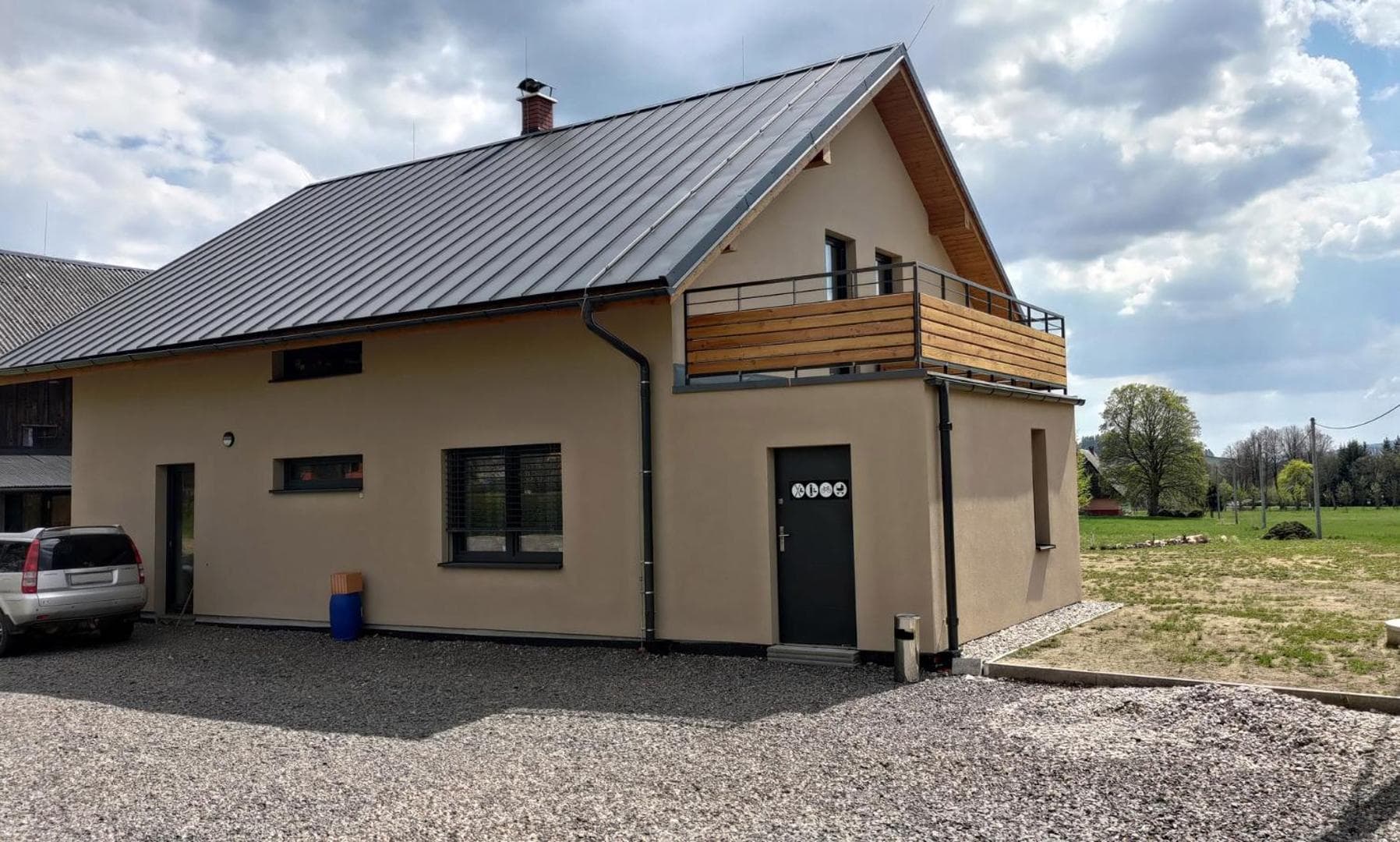 Vchod do domu s balkonem, kolárnou a parkováním